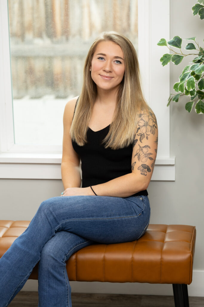 Woman sitting on bench in black tank top during brand session in Utah.