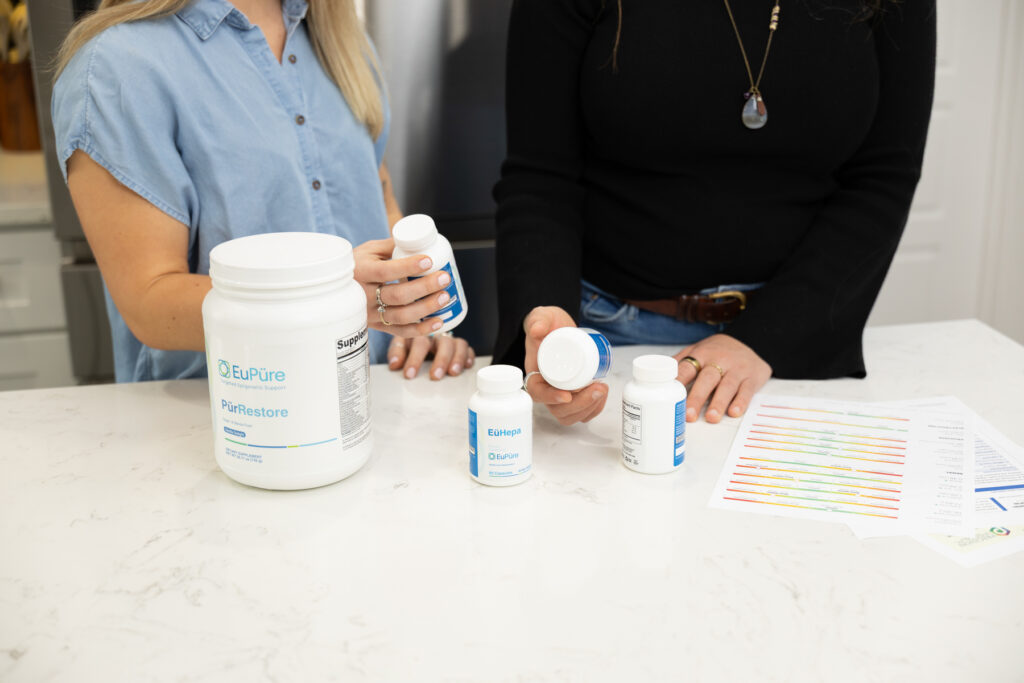 Close up of supplement bottles during a brand shoot while two women are talking about the benefits.