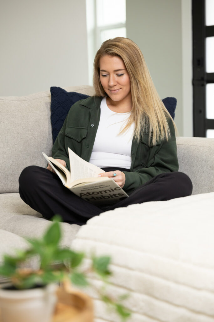 Woman reading a book while sitting on a couch during brand shoot.