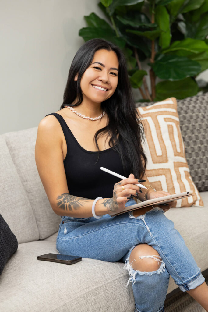 Woman smiling at camera while communicating with clients on her iPad during a brand shoot.