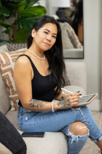 Woman posing during a brand shoot while working on her iPad with clients.