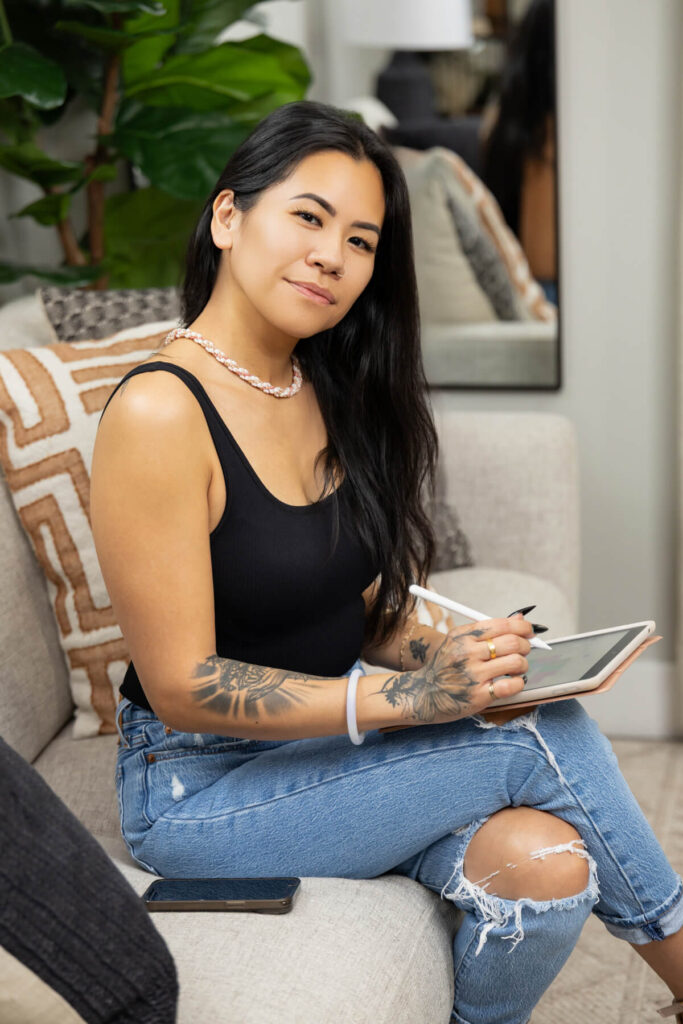 Woman posing during a brand shoot while working on her iPad with clients.