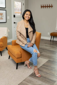 Smiling woman sitting on edge of seat during brand session with Sara Vaz in Utah.