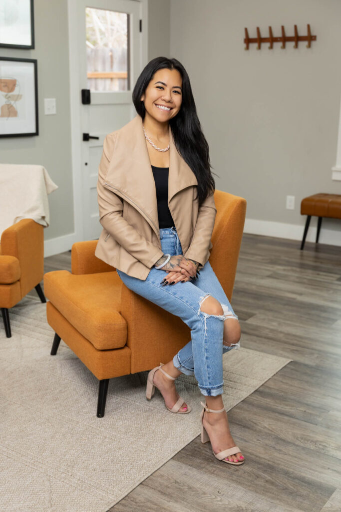 Smiling woman sitting on edge of seat during brand session with Sara Vaz in Utah.